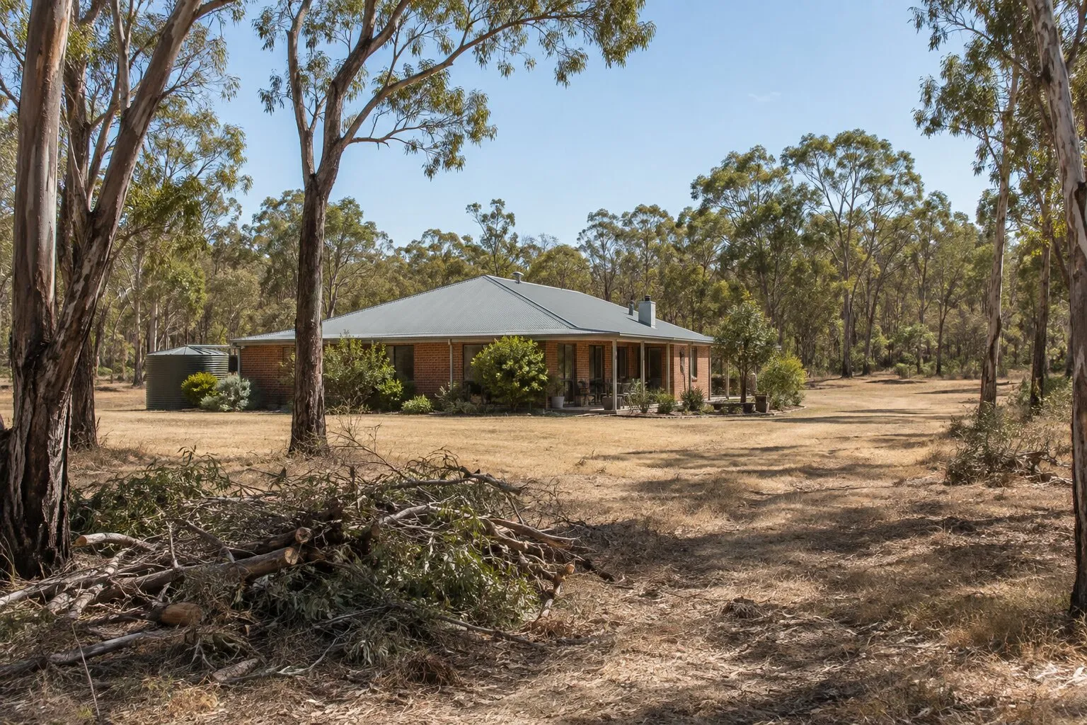 Bushfire clearing, Bendigo: bush block with trees cleared back from a brick home and branches piled for chipping